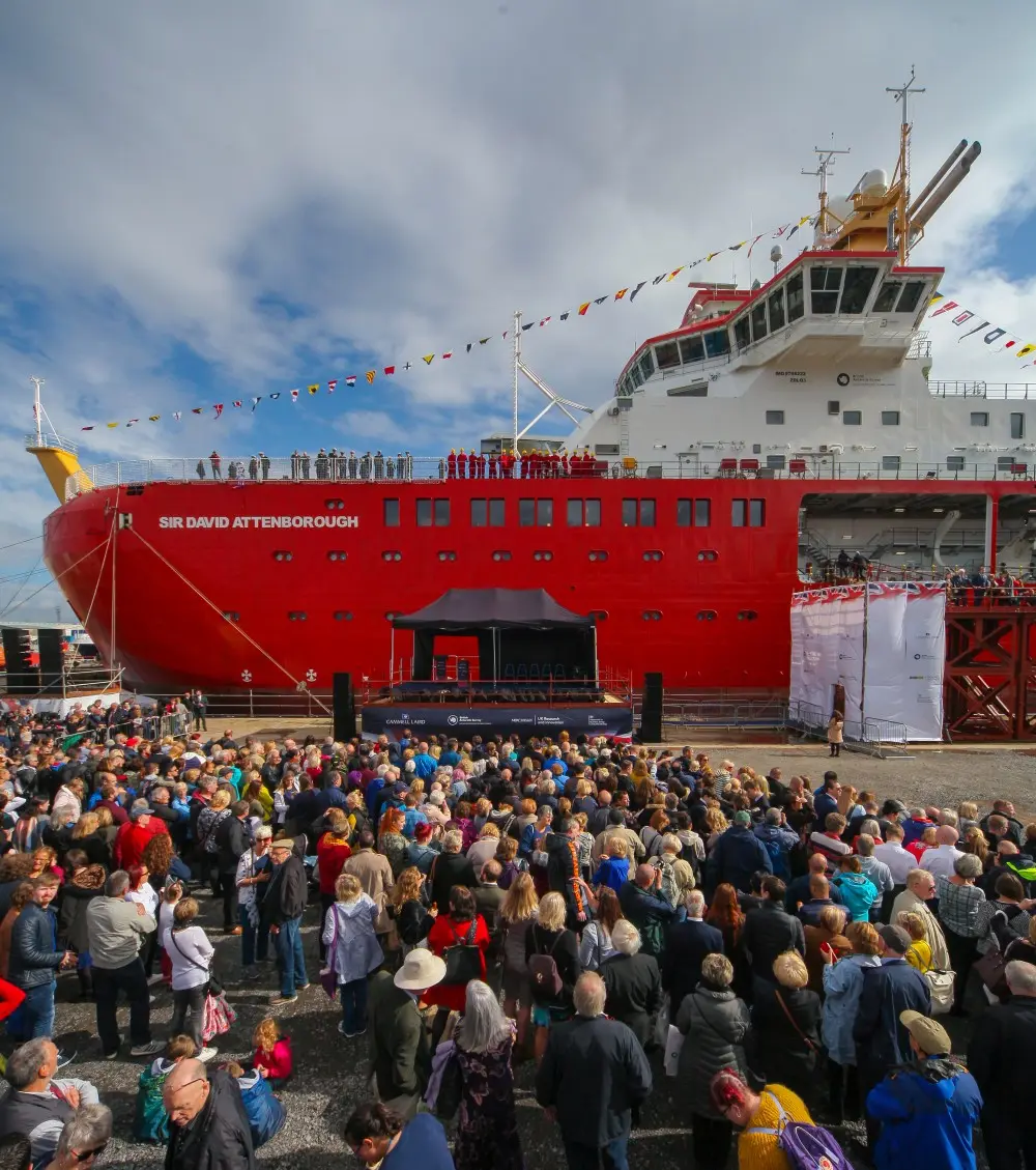 Crowd gathered in front of a red research icebreaker at the shipyard